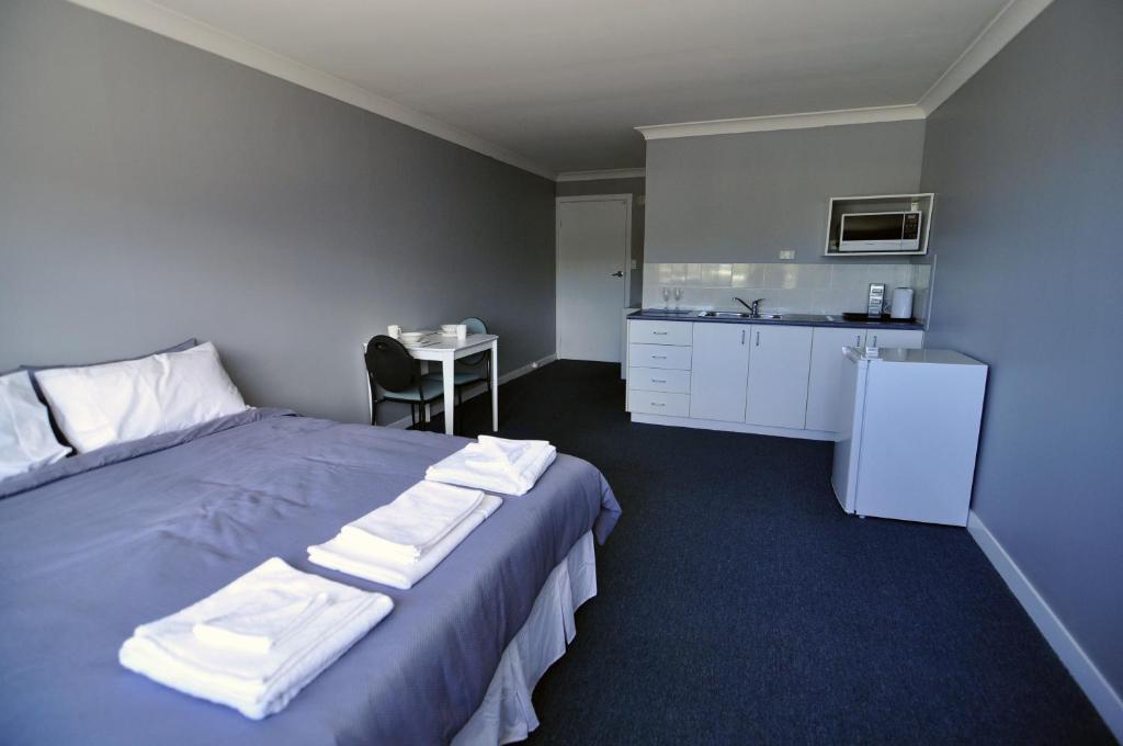 a hotel room with a bed and a kitchen at Bribie Island Square in Bongaree