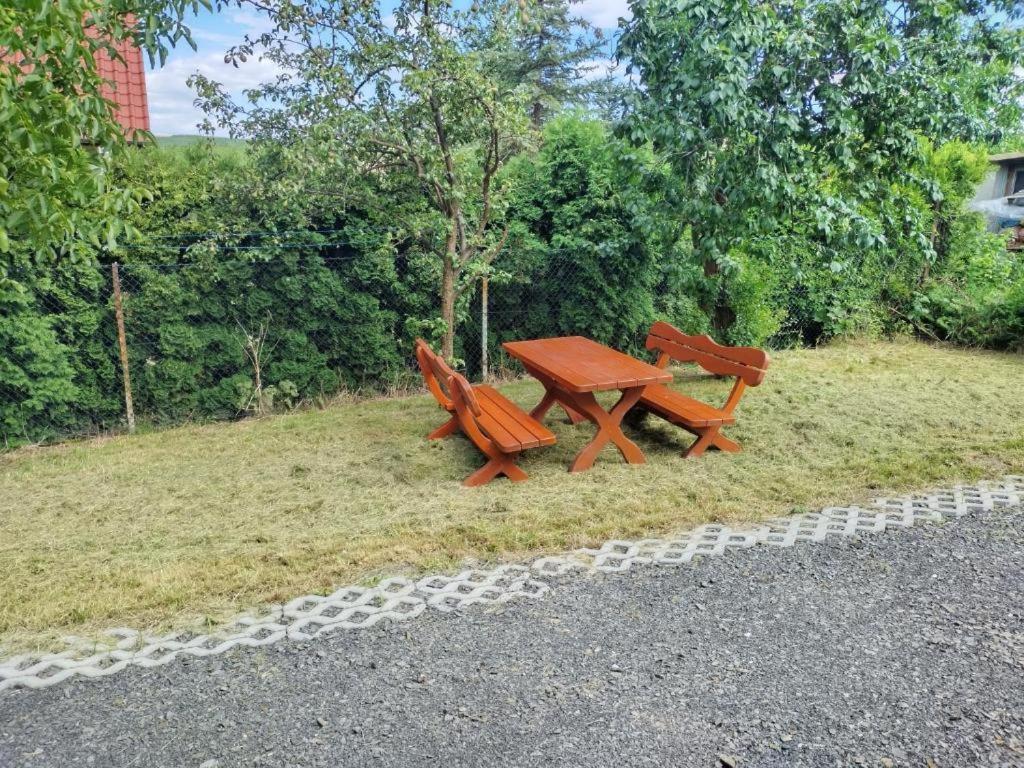 dwie ławki i stół piknikowy w trawie w obiekcie Szary Domek 2 w mieście Wieprz