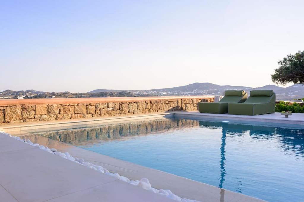 a swimming pool with a couch sitting next to a wall at Myconian Mythodea Luxury Villa in Ano Mera