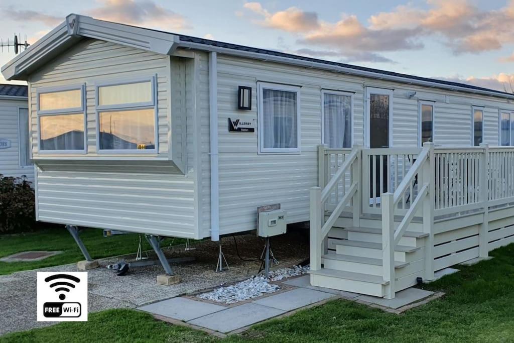 ein winziges Haus mit einer Veranda und einer Treppe in der Unterkunft Brookside West Sands Holiday Park Seal Bay Selsey in Selsey