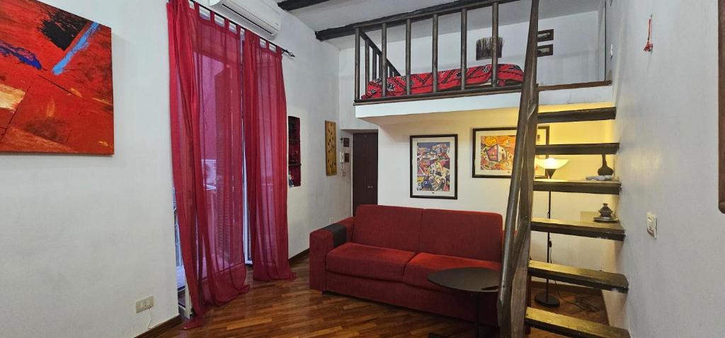 un soggiorno con divano rosso e letto a soppalco di Chiaia Maison a Napoli