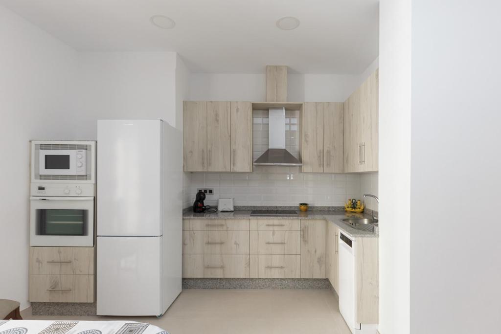 una cocina con electrodomésticos blancos y armarios de madera en apartamentos El-Hizan, en Laujar de Andarax