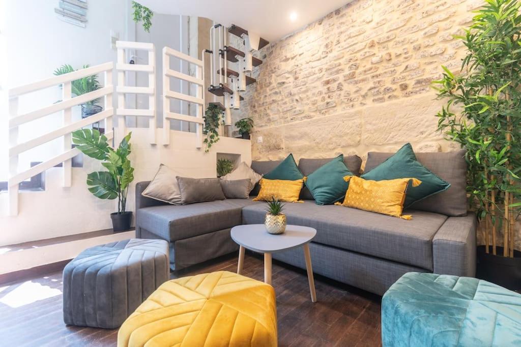 un salon avec un canapé et un mur de briques dans l'établissement Duplex Parisien charmant en face métro13, à Paris