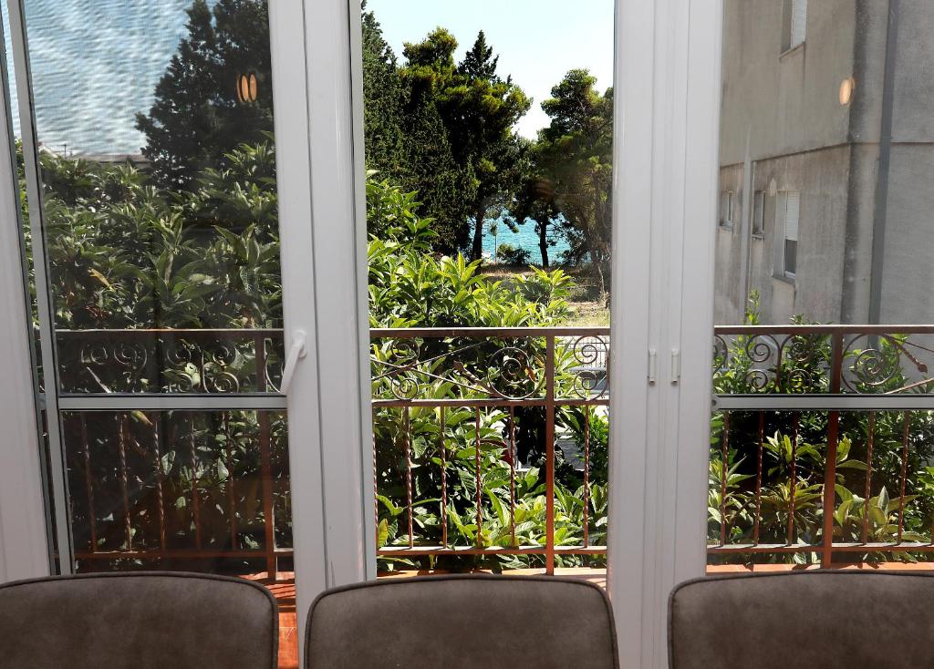 - deux chaises devant une fenêtre donnant sur un jardin dans l'établissement APARTMAN NEŠPULA 3, à Kaštela