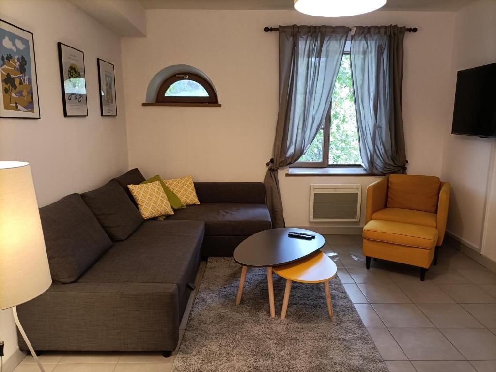ein Wohnzimmer mit einem Sofa, einem Tisch und einem Stuhl in der Unterkunft Le Petit Nid de Nant in Nant