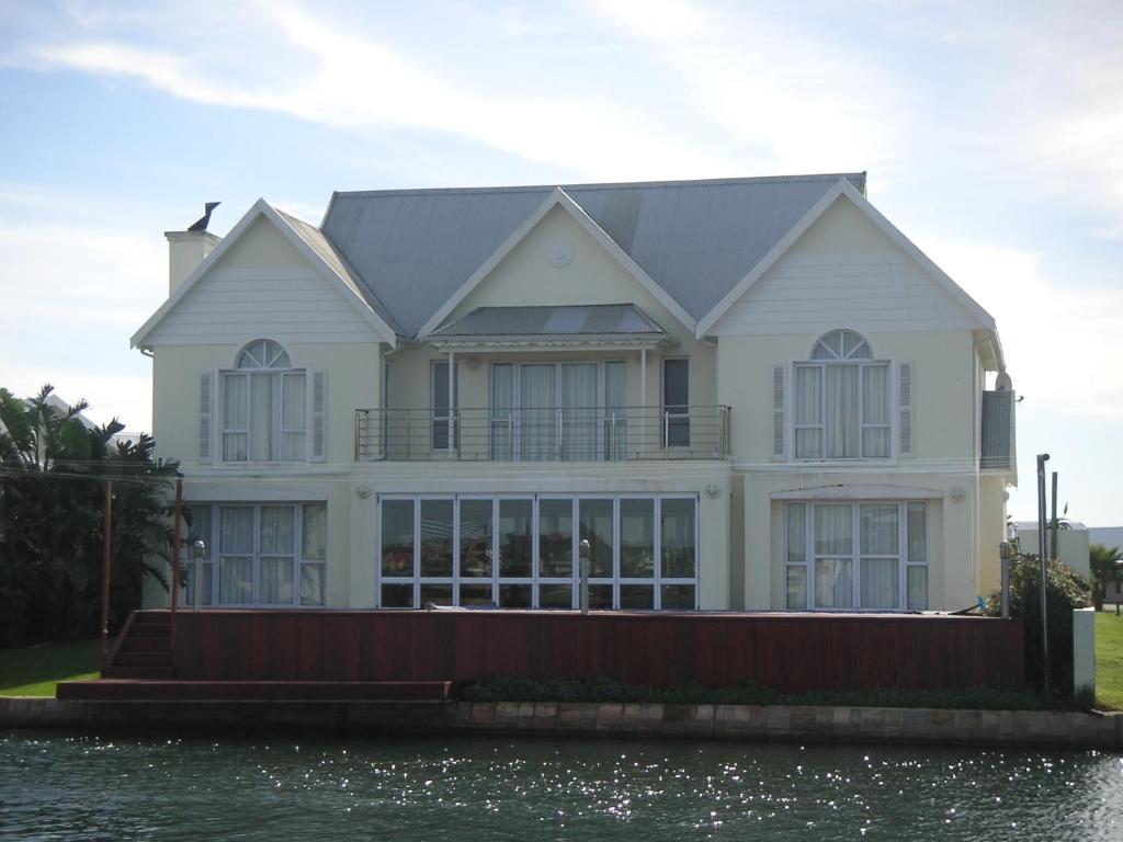 Una gran casa blanca sobre el agua junto al agua. en Waterside Living MM1394, en Jeffreys Bay