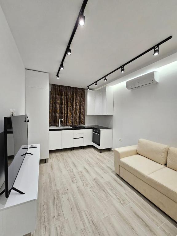 een witte woonkamer met een bank en een keuken bij Vila 4G in Tirana