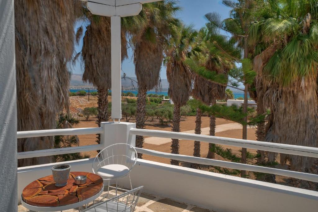 a table and a chair on a balcony with palm trees at Palm Heaven Boutique Apartments in Antiparos Town