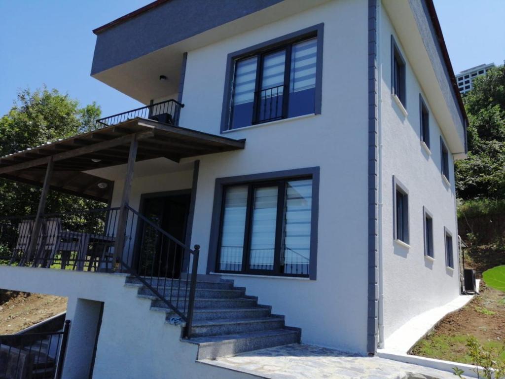 uma casa branca com escadas e janelas em Kiralık Lüx Deniz Manzaralı Bahçeli Villa/Luxury Sea View Garden Villa for Rent em Trabzon