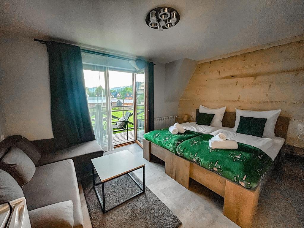 a bedroom with a bed and a couch and a window at Ustup 25 in Zakopane
