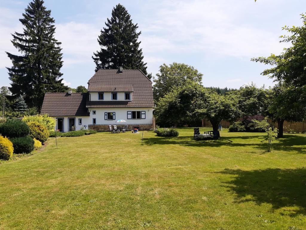 une maison blanche avec une cour herbeuse arborée dans l'établissement DOM W SUDETACH, 