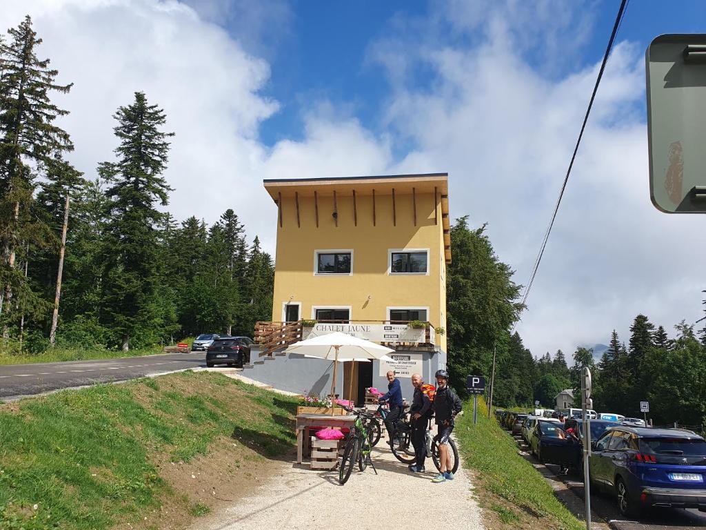 a group of people riding bikes on a sidewalk in front of a building at Chalet Jaune Le GRAND SOM in Sarcenas