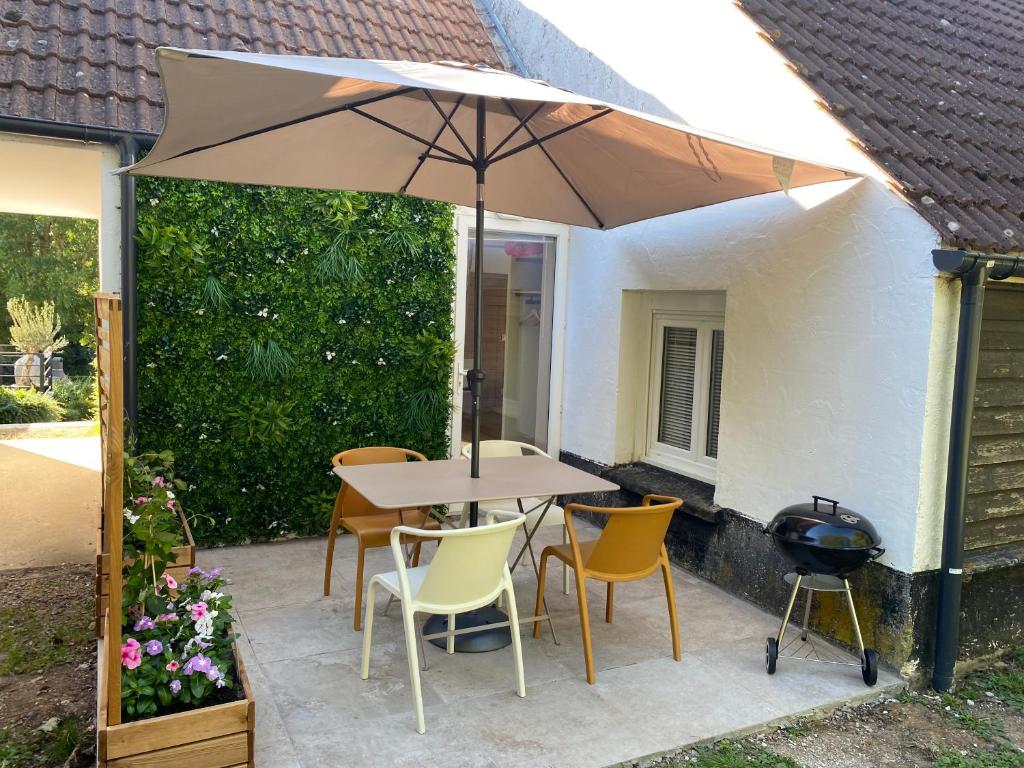 a table and chairs with an umbrella on a patio at Le Nid du Cygne in Houlle