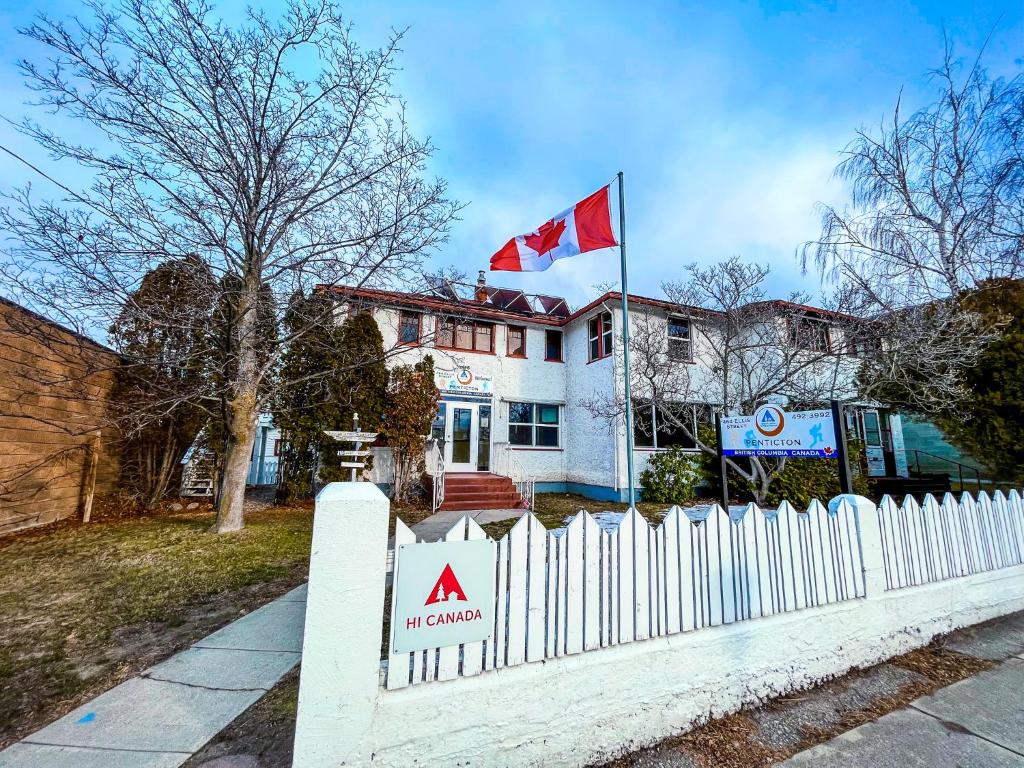 una cerca blanca frente a una casa con bandera canadiense en HI Penticton - Hostel, en Penticton