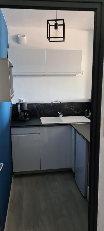 a kitchen with white cabinets and a black counter top at F2 confortable Carnon-Plage in Carnon-Plage