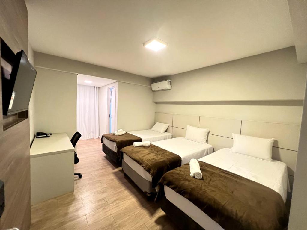 una camera d'albergo con due letti e una televisione di SG Apart Hotel a São Gonçalo do Rio Abaixo