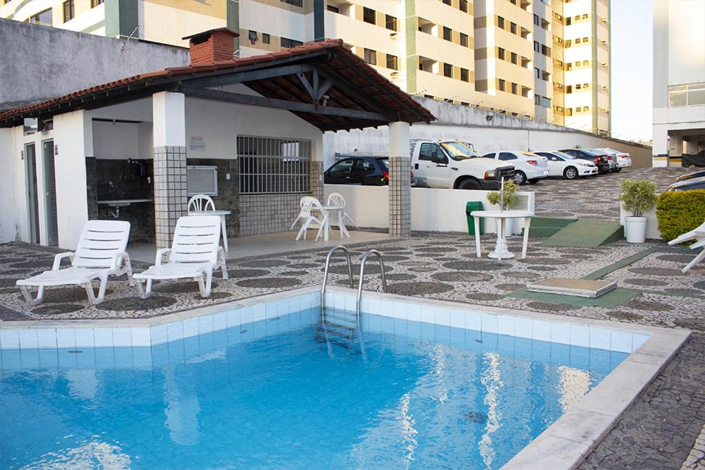 una piscina con sillas, una mesa y un edificio en Apto Stiep Inteiro, en Salvador