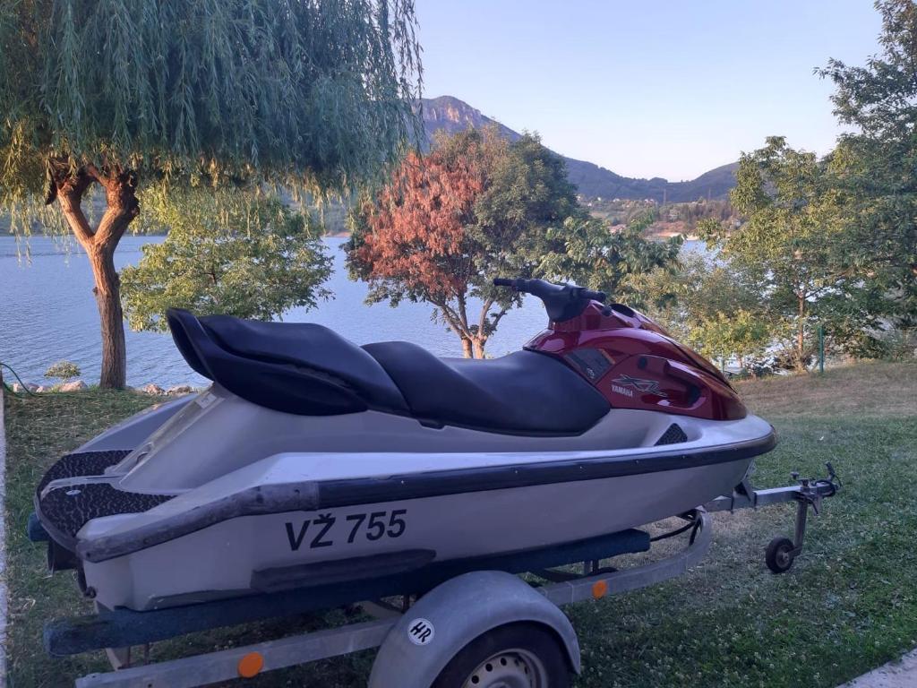 a motor boat parked on a trailer next to a lake at Kuća za odmor Oaza mira in Kovačevo Polje