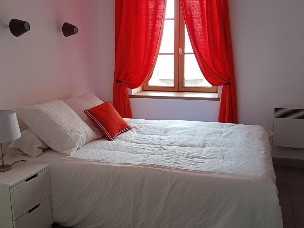 a bedroom with a bed with red curtains and a window at La Jolie Dourbie de Nant in Nant