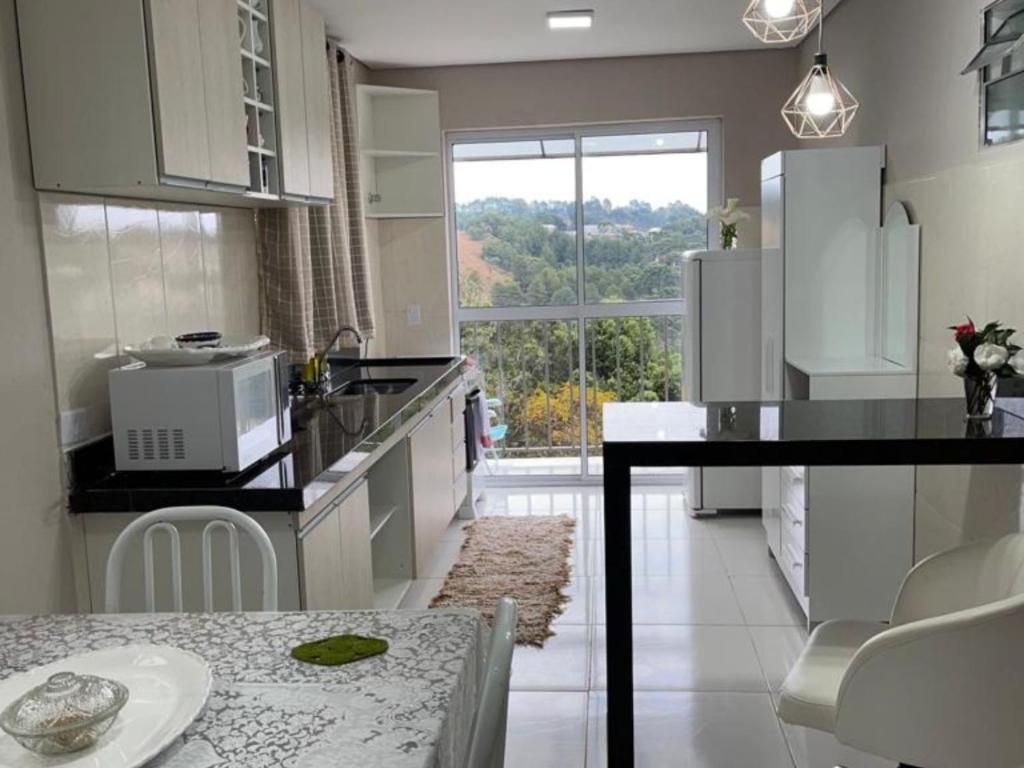 a kitchen with white appliances and a table and a window at Dith's House in Campos do Jordão