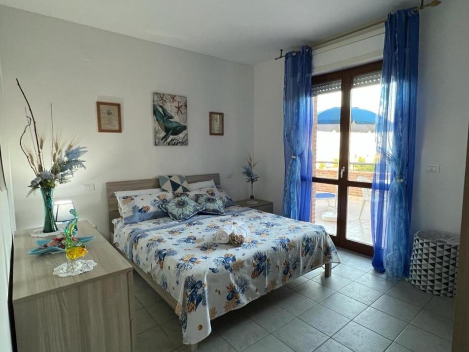 um quarto com uma cama com cortinas azuis e uma janela em STELLA DI MARE em Marina di San Vito