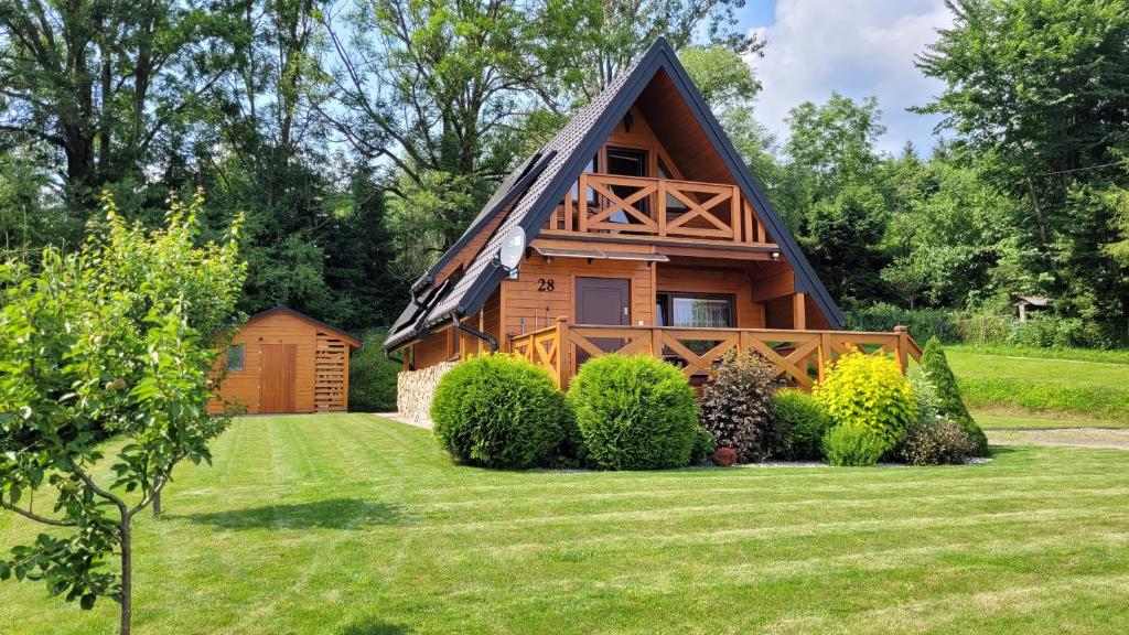 a log cabin with a green yard in front of it at Domek w Bieszczadach in Lutowiska