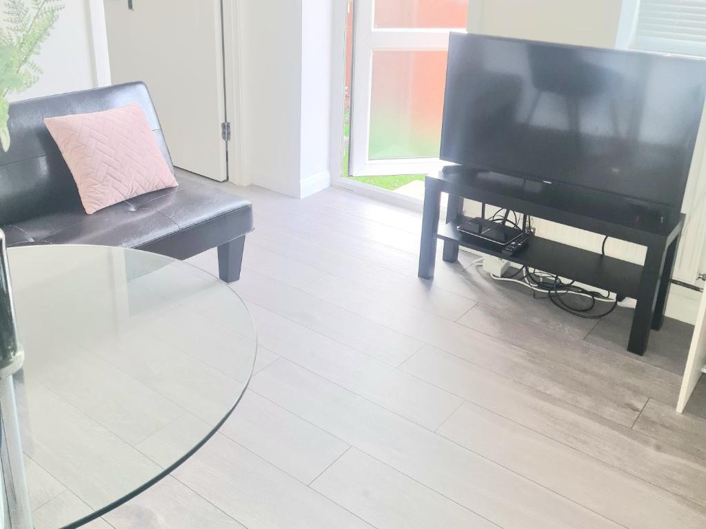 a living room with a tv and a chair and a table at Modern 2 Bedroom Flat With Garden LONDON in Northolt