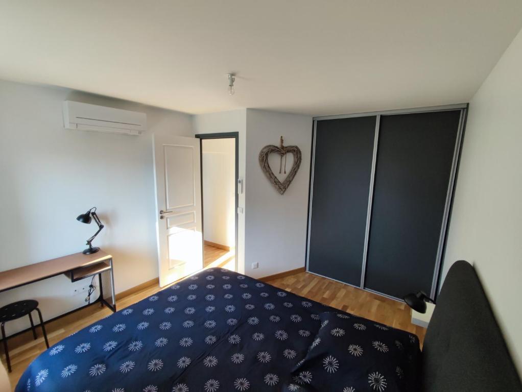 Un dormitorio con una cama azul y un corazón en la pared en Maison indépendante à Peyrieu en Peyrieu
