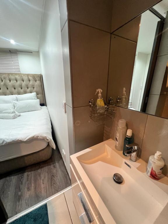 a bathroom with a sink and a bed and a mirror at Sky View Escape in Windhoek