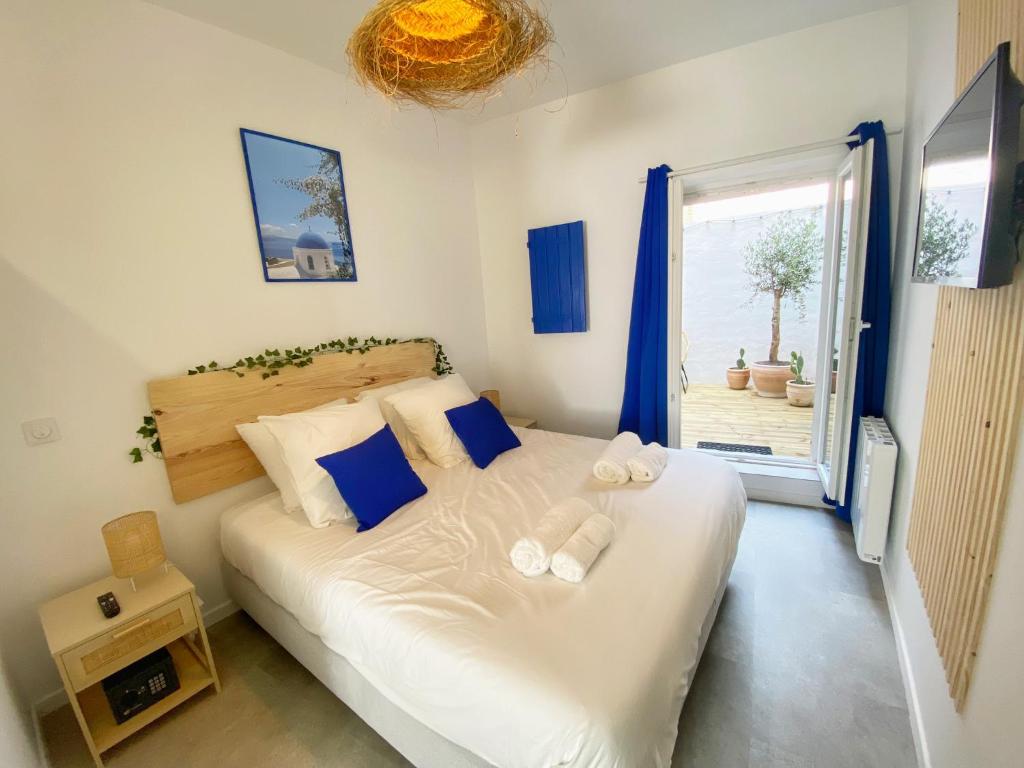 een slaapkamer met een wit bed met blauwe kussens en een raam bij Le Santorini - centre ville & terrasse privée in Béthune