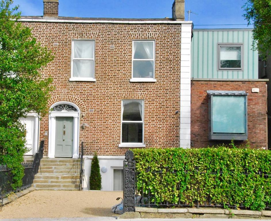 uma casa de tijolos com uma porta branca e uma sebe em Dublin Apartments em Dublin