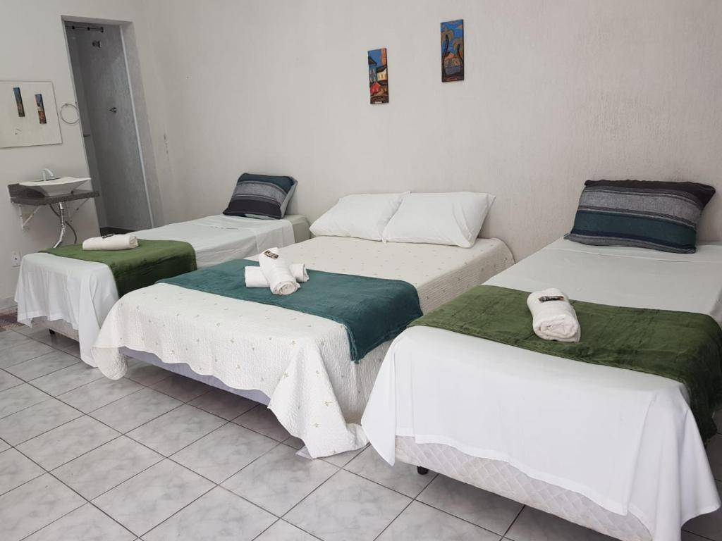 a group of four beds in a room at FLAT 2 - CENTRO DE ITAPIRA in Itapira