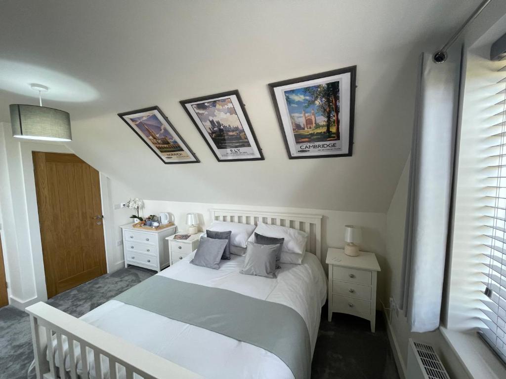 sypialnia z białym łóżkiem i zdjęciami na ścianie w obiekcie The Top Floor w mieście Stretham