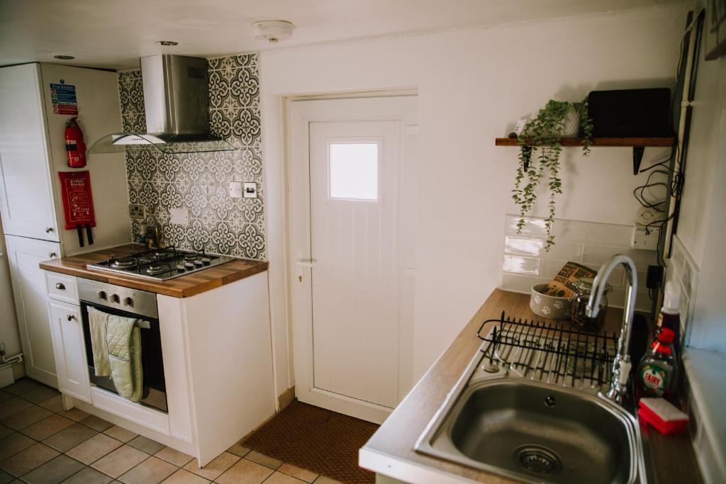 eine kleine Küche mit einer Spüle und einem Herd in der Unterkunft Pebbles Cottage in Caister-on-Sea