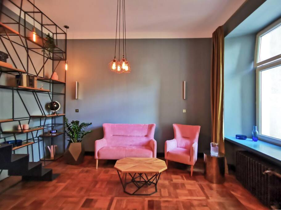 sala de estar con 2 sillas rosas y mesa en Butikowy apartament w centrum Warszawy, en Varsovia