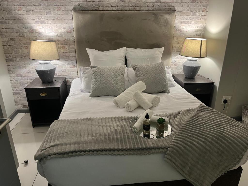 een slaapkamer met een groot bed met 2 lampen bij The Den in Windhoek