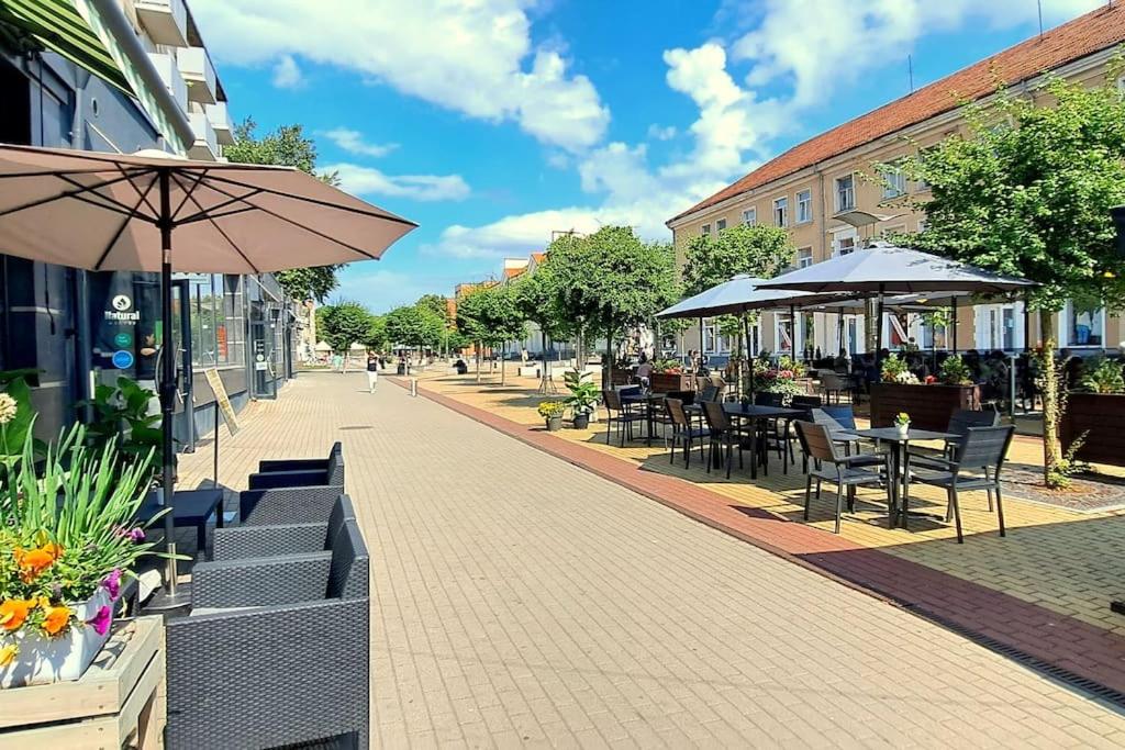 an empty street with tables and chairs and umbrellas at Self Check-In Loft in Klaipeda city centre Free Parking in Klaipėda