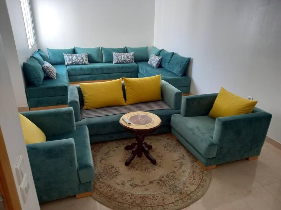 een woonkamer met een blauwe bank en gele kussens bij Appartement Agadir Salam in Agadir