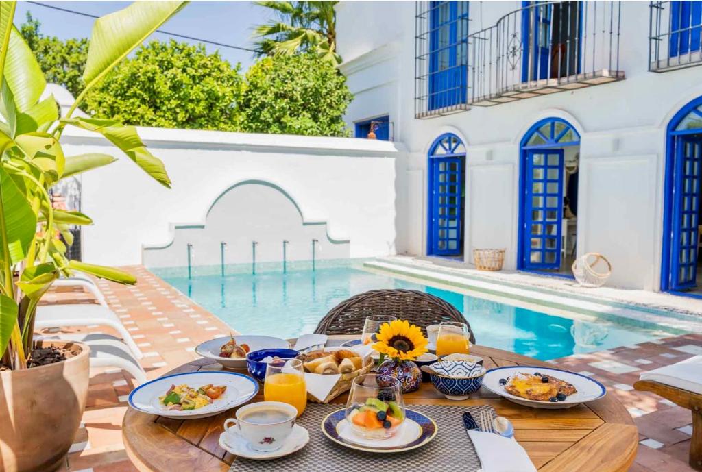 a table with breakfast food next to a swimming pool at The Pearl - Marbella in Marbella
