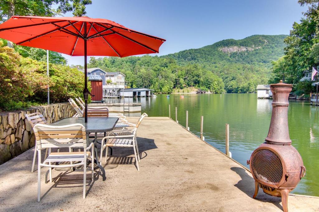 a table and chairs with an umbrella next to a lake at Waterfront Home with Dock Access on Lake Lure! in Lake Lure