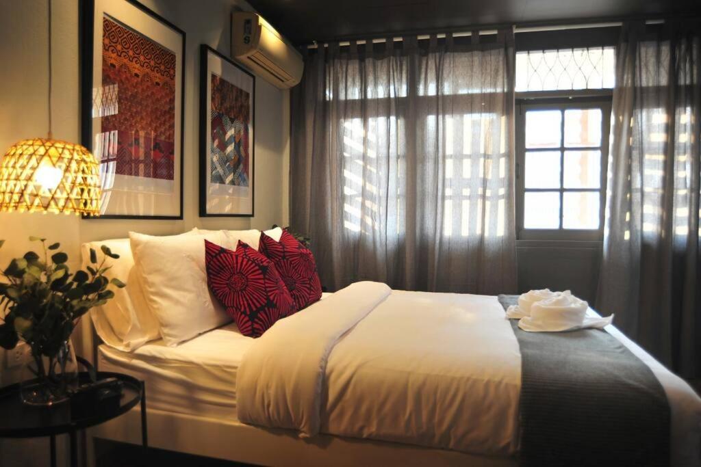 a bedroom with a bed with red pillows and a window at Kratib House @ MRT Queen Sirikit 400m in Bangkok