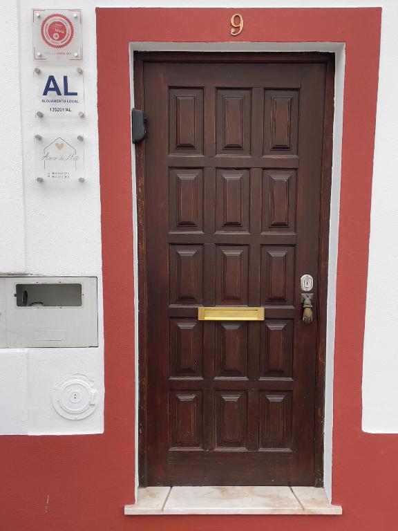 a brown door on a red and white building at Alojamento Amor de Mãe in São Teotónio