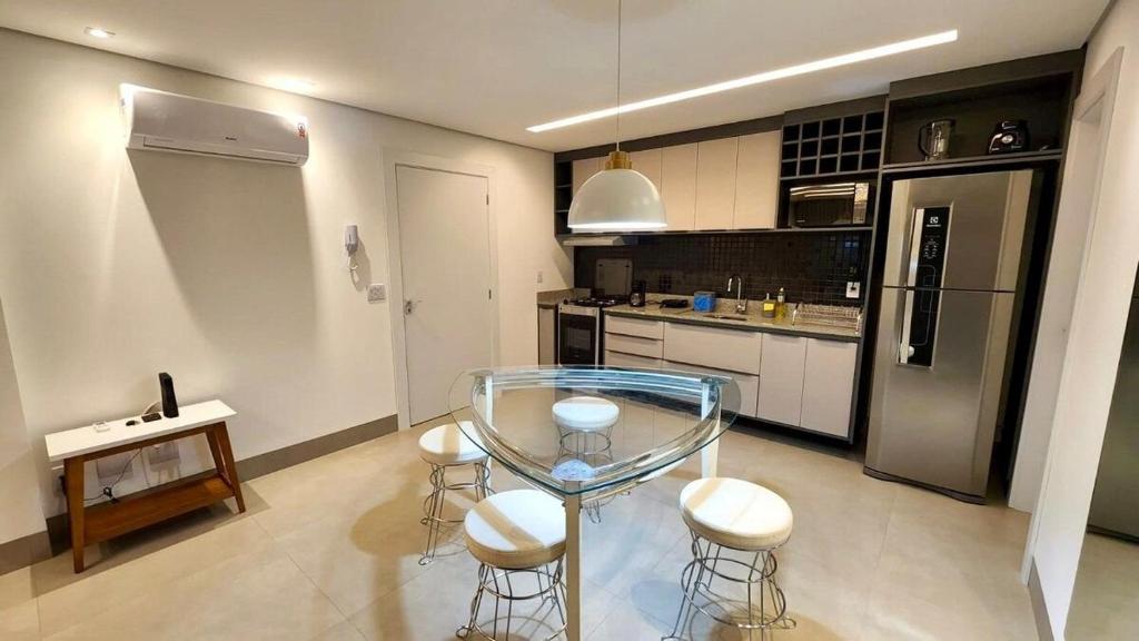una cucina con tavolo in vetro e sgabelli di Loft Amplo e Aconchegante c/ Quarto Privativo a Campo Grande