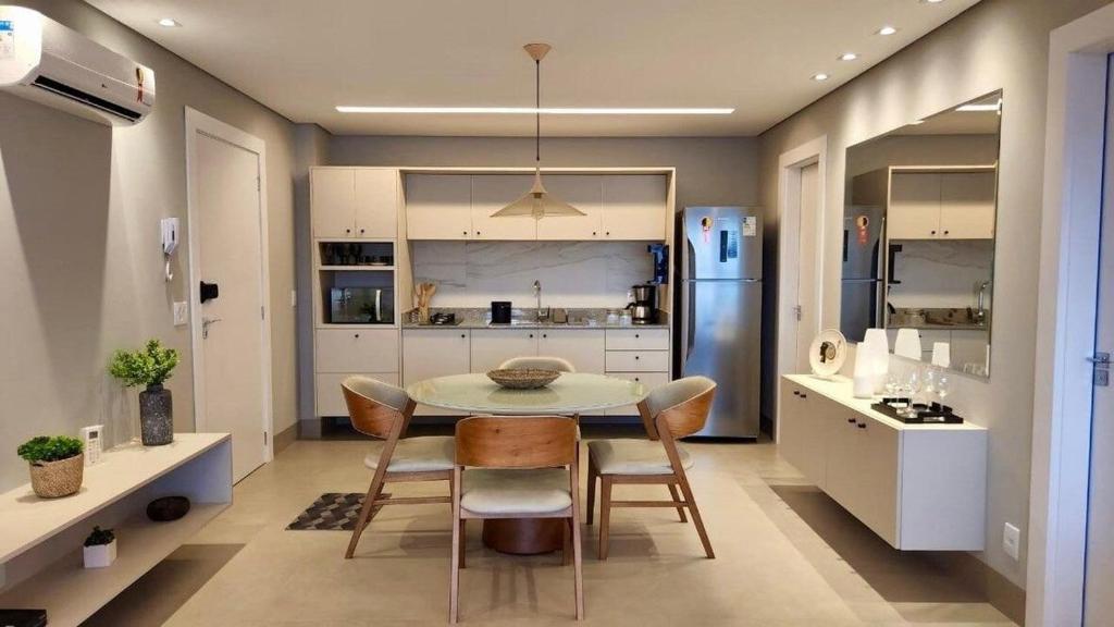 uma cozinha com uma mesa e cadeiras e um frigorífico em Loft Ultra Luxo há Poucos Passos do Shopping CG. em Campo Grande
