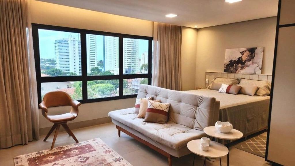 a bedroom with a couch and a bed with a large window at Loft de Luxo há Poucos Passos do Shopping CG in Campo Grande