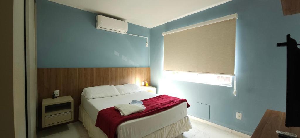 um quarto com uma cama com um cobertor vermelho em Residencial Nicole em Florianópolis