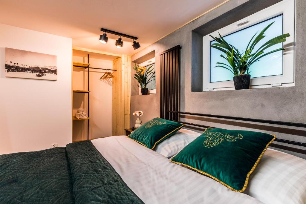 a bedroom with a bed with green pillows and a window at Apartament Żubry z Sauna in Zakopane