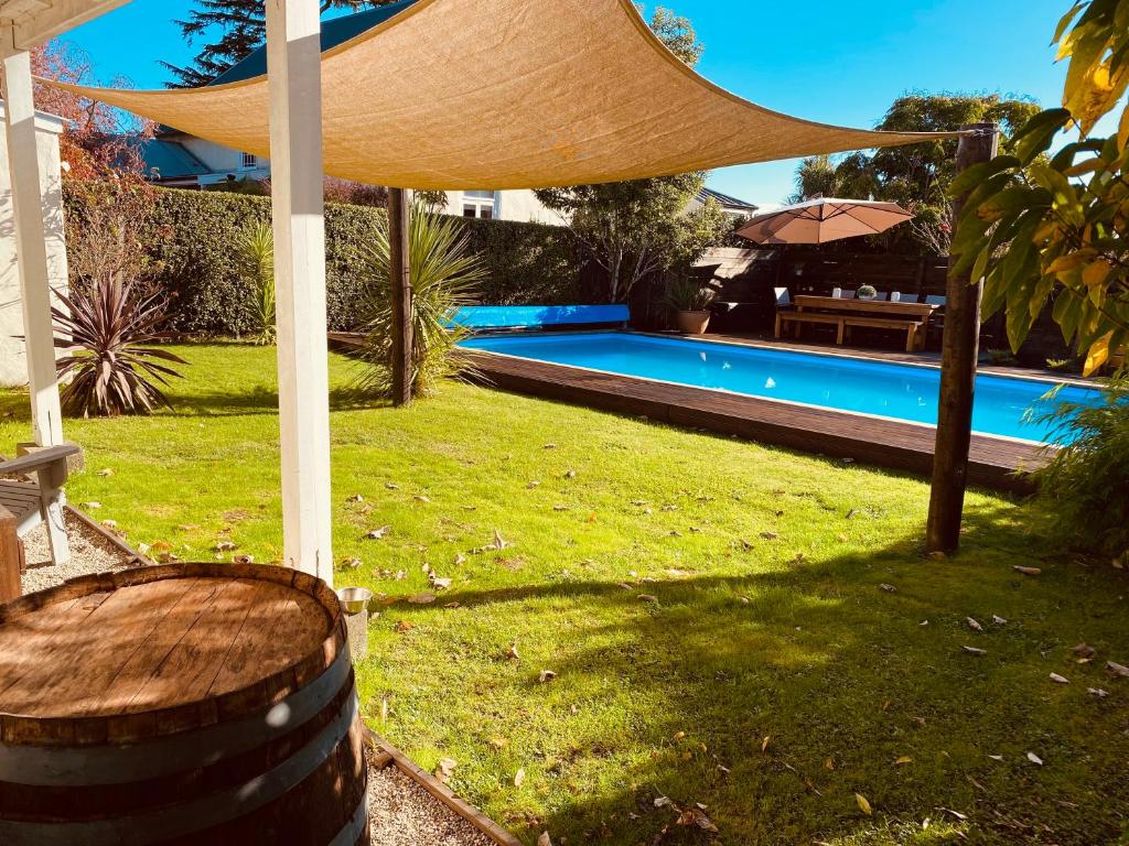 um quintal com uma piscina com um guarda-sol e um barril em Woodstock Suite em Nelson
