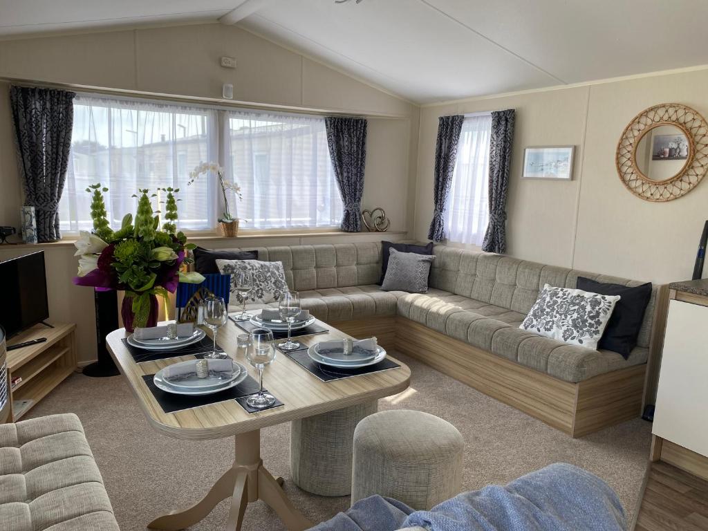 a living room with a couch and a table at Comfy Cosy Caravan_Romney Sands in Littlestone-on-Sea