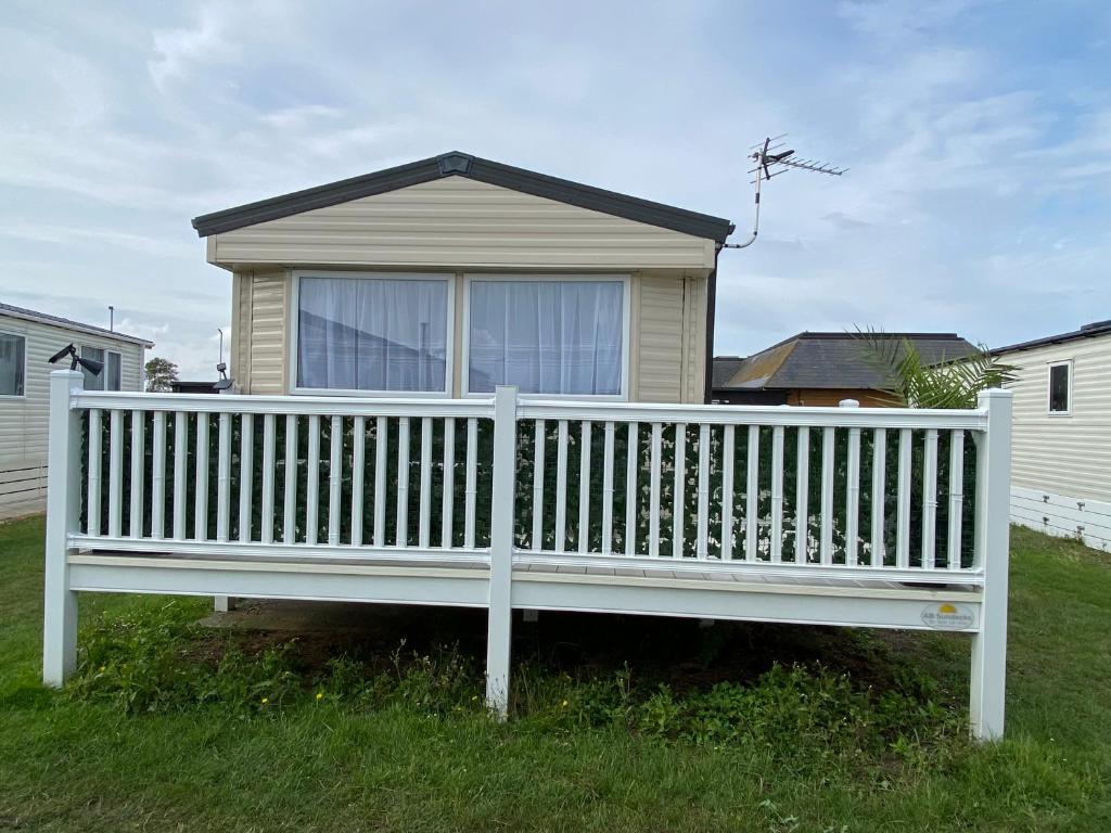 a white wooden bench in front of a house at Comfy Cosy Caravan_Romney Sands in Littlestone-on-Sea